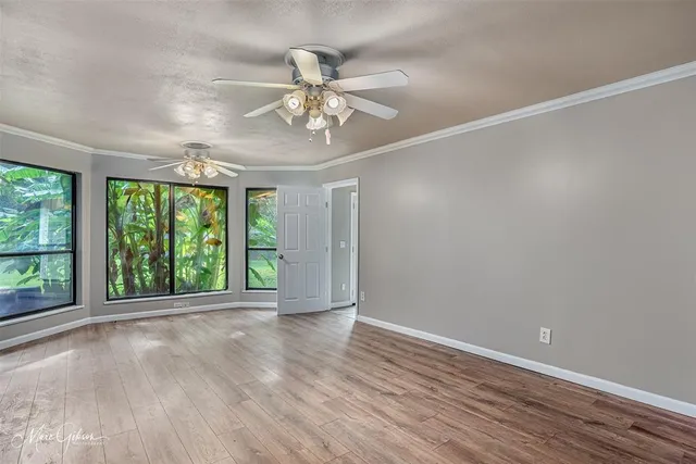 a view of an empty room with a window and wooden floor