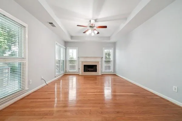 an empty room with wooden floor fireplace and windows