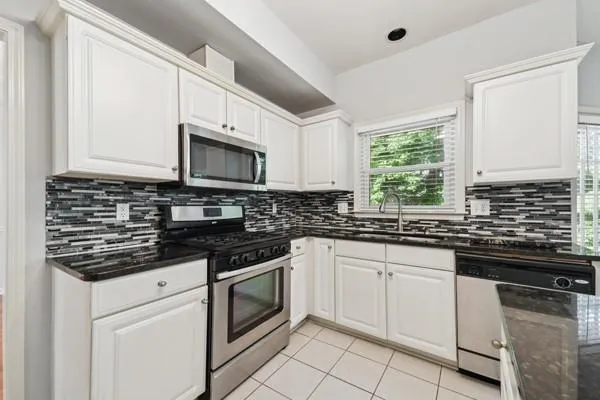 a kitchen with stainless steel appliances granite countertop a stove a sink and a microwave