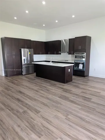 a large kitchen with stainless steel appliances wooden cabinets and wooden floor