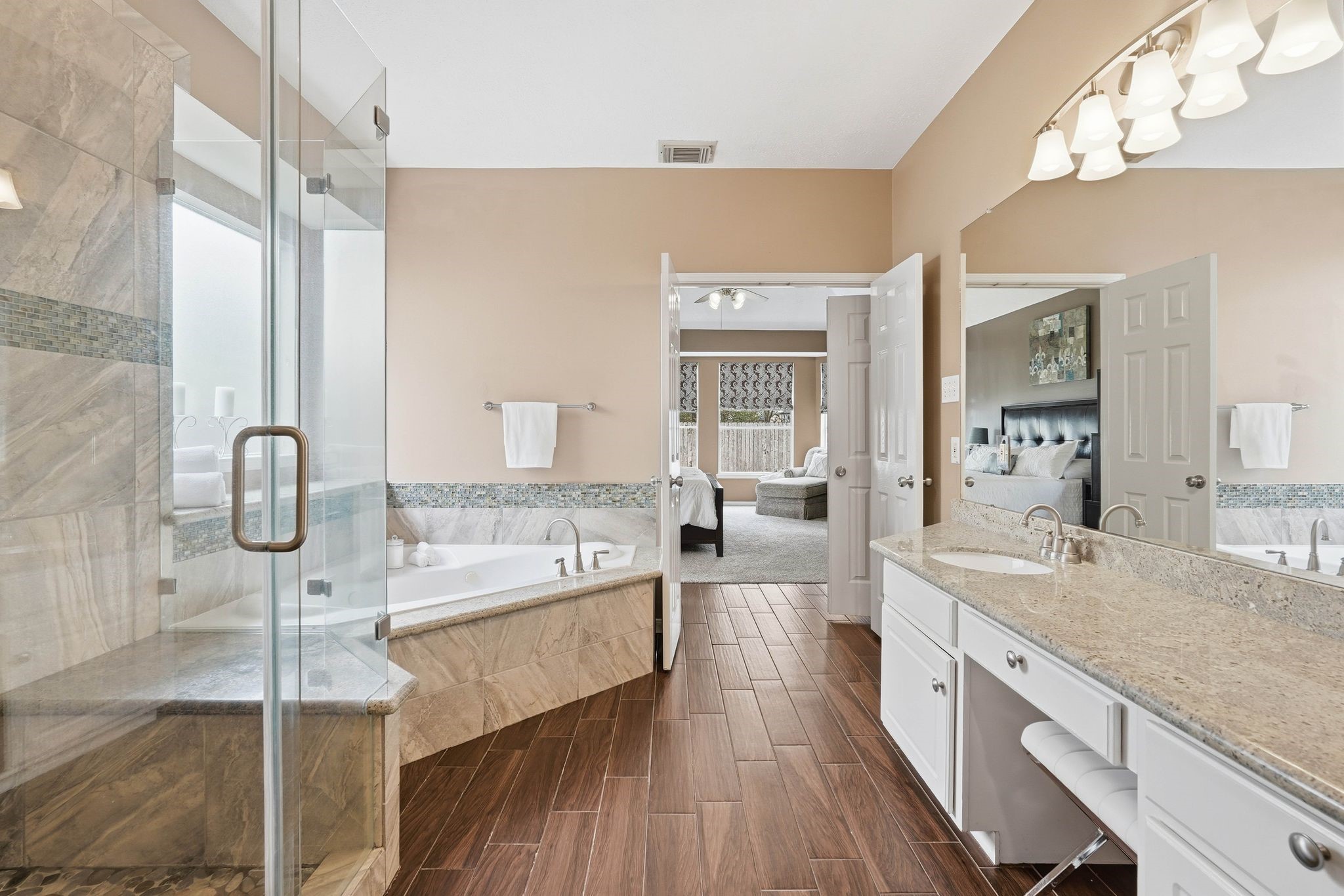 2515 Woodsboro Drive Spring, TX 77388 - Photo 23 of 44 This spacious primary bathroom features a luxurious glass-enclosed shower, a large soaking tub, dual sinks with granite countertops, and elegant flooring. It opens into a bright bedroom, creating a seamless and inviting layout.