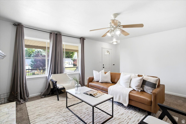 1341 29th Street Ogden, UT 84403 - Photo 7 of 37 Living area featuring a ceiling fan with light fixture, carpet flooring, a white paneled entry door, and a pair of large windows overlooking the exterior porch