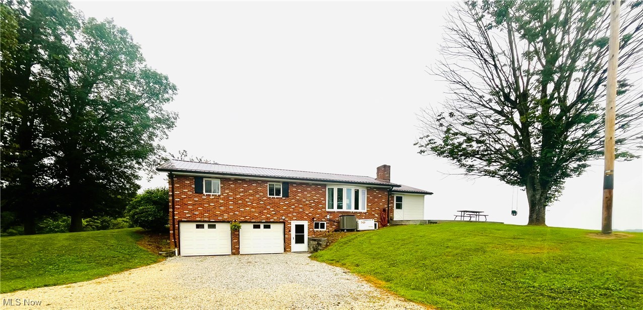 91070 Kilgore Ridge Road Scio, OH 43988 - Photo 26 of 40 View of front of home featuring gravel driveway, a chimney, a garage, and a front lawn