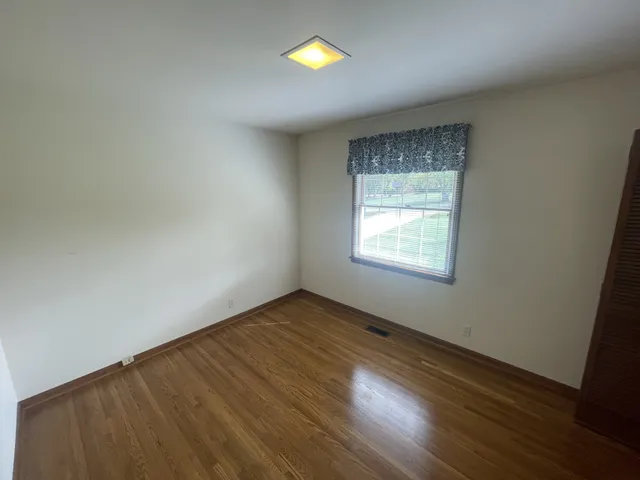an empty room with wooden floor and chandelier