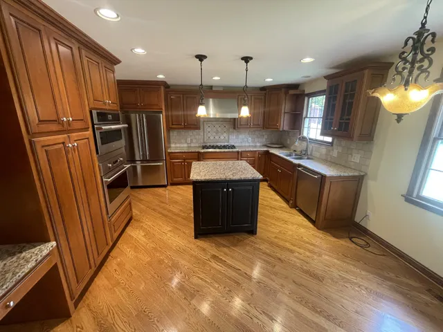 a kitchen with stainless steel appliances granite countertop a refrigerator a sink and a stove