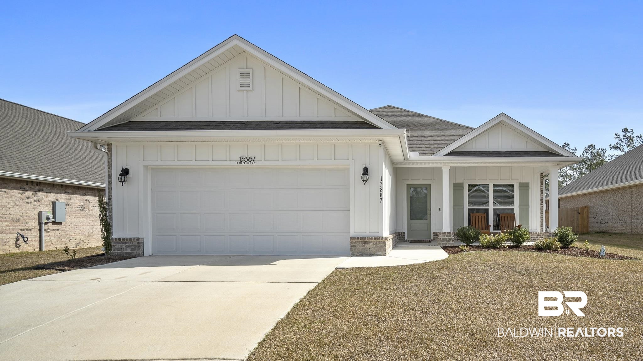 View of front of property with board and batten siding, a shingled roof, an attached garage, covered porch, and driveway