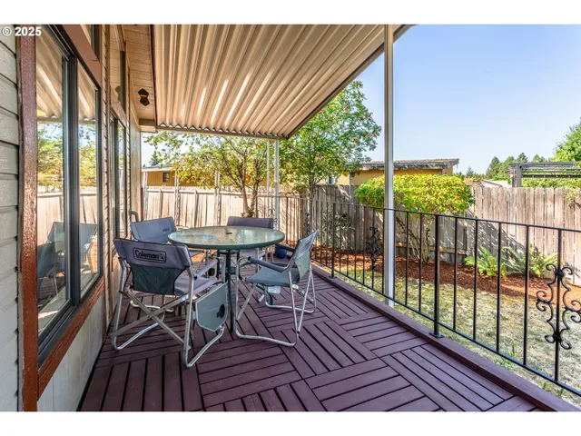 a view of a patio with table and chairs with wooden floor and fence