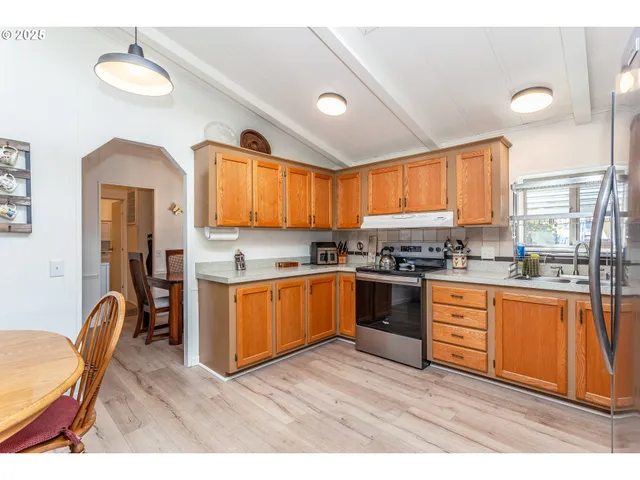 a kitchen with stainless steel appliances granite countertop a refrigerator a sink dishwasher a stove with wooden cabinets