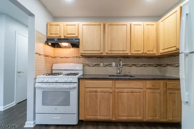 a kitchen with granite countertop cabinets appliances and a sink