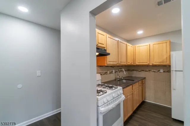 a kitchen with stainless steel appliances granite countertop a stove a sink and a refrigerator with wooden floor