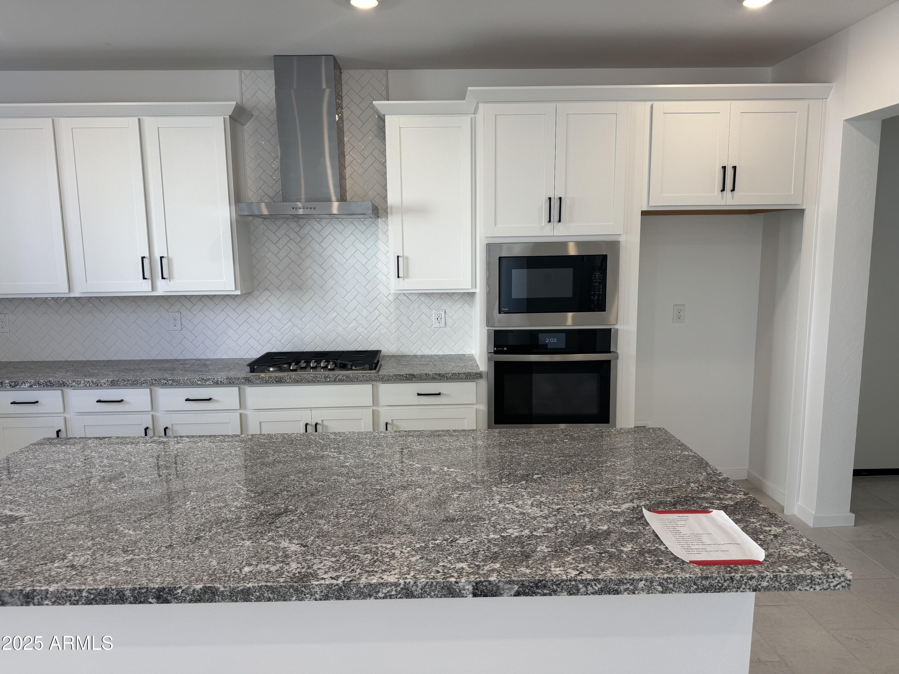 2454 West Maximo Way Phoenix, AZ 85085 - Photo 5 of 27 a kitchen with kitchen island white cabinets and stainless steel appliances