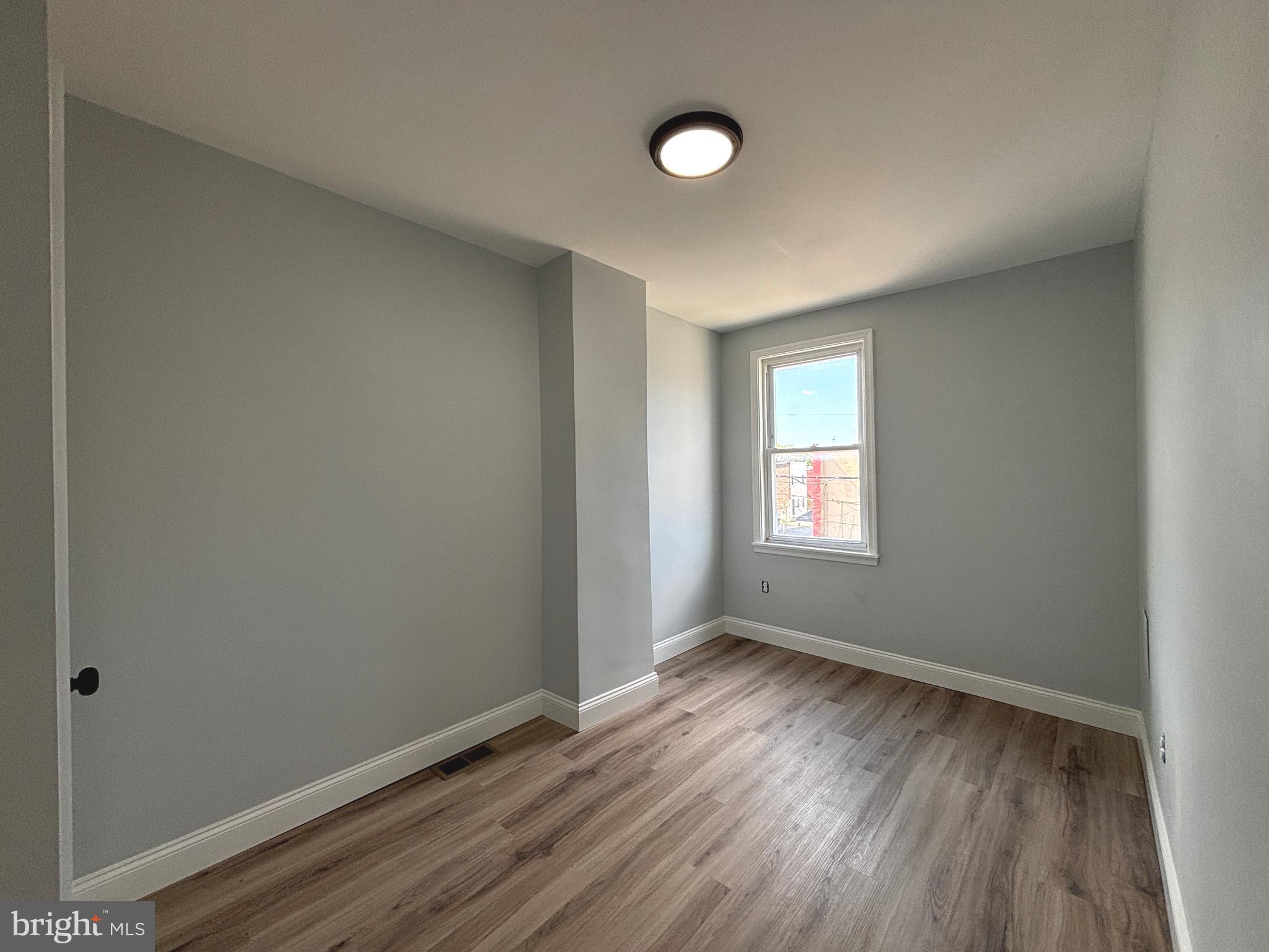 2636 Harford Road Baltimore, MD 21218 - Photo 15 of 18 a view of an empty room with wooden floor and a window
