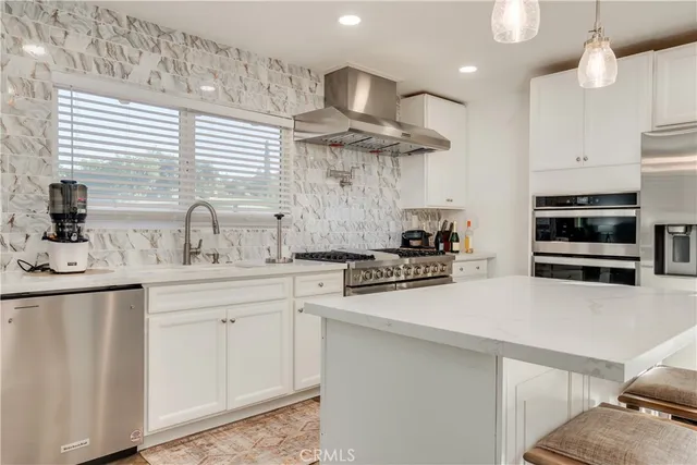 a kitchen with stainless steel appliances a sink a stove a refrigerator cabinets and a window