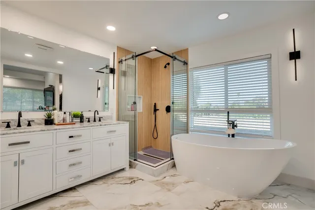 a bathroom with a granite countertop sink a mirror a bathtub and shower