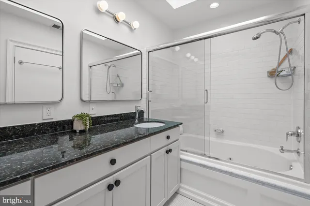 a bathroom with a granite countertop sink a toilet and shower