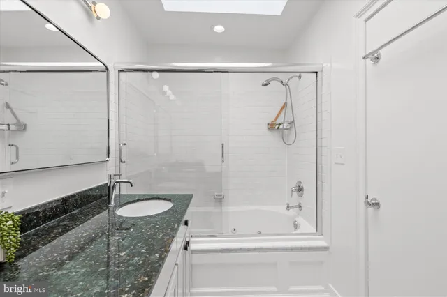 a bathroom with a granite countertop shower sink vanity and mirror