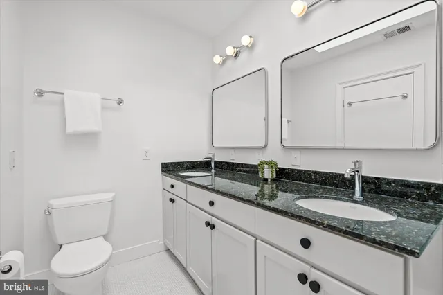 a bathroom with a granite countertop toilet sink and mirror