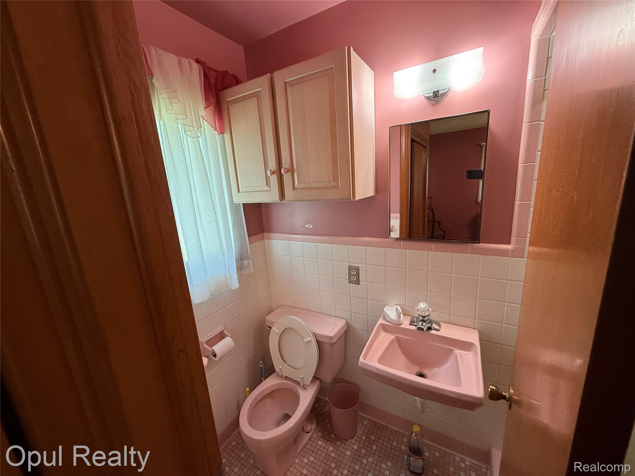 7899 Ida East Road Ida, MI 48140 - Photo 38 of 48 Bathroom featuring a pink wall-mounted sink, pink toilet, and white wall tiles