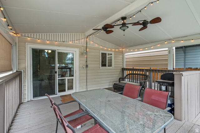7659 State Street Midvale, UT 84047 - Photo 27 of 33 Covered outdoor deck featuring a ceiling fan with integrated lighting, string lights, sliding glass door access, and a wooden railing
