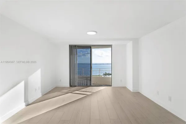 a view of a bedroom with wooden floor and window
