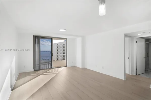 a view of an empty room with window and wooden floor