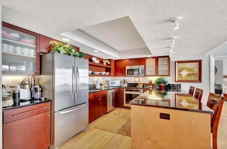 4200 North Ocean Drive, Unit 1905 Singer Island, FL 33404 - Photo 19 of 38 a kitchen with stainless steel appliances granite countertop a refrigerator a sink dishwasher a stove and a dining table with wooden floor