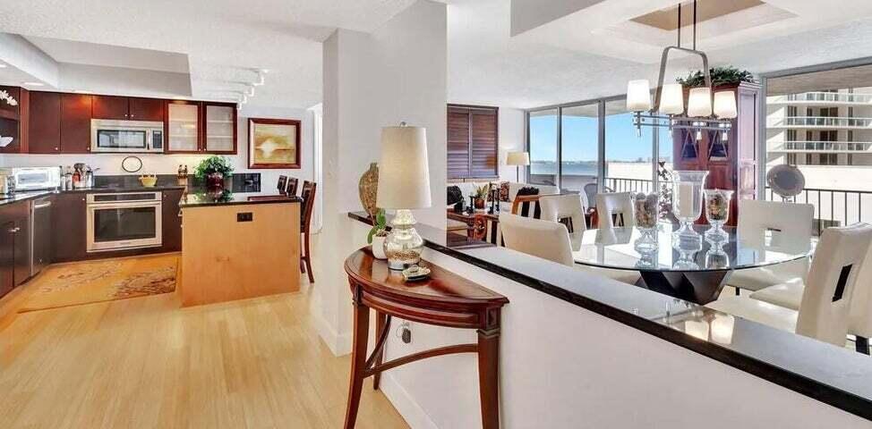 4200 North Ocean Drive, Unit 1905 Singer Island, FL 33404 - Photo 33 of 38 a kitchen with stainless steel appliances kitchen island granite countertop a stove a sink dishwasher a dining table and chairs with wooden floor