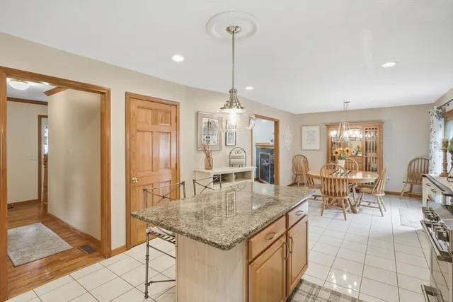 a dining hall with stainless steel appliances granite countertop a dining table chairs and chandelier