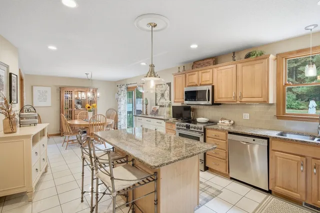 a kitchen with stainless steel appliances granite countertop a stove top oven a sink dishwasher a dining table and chairs with wooden floor