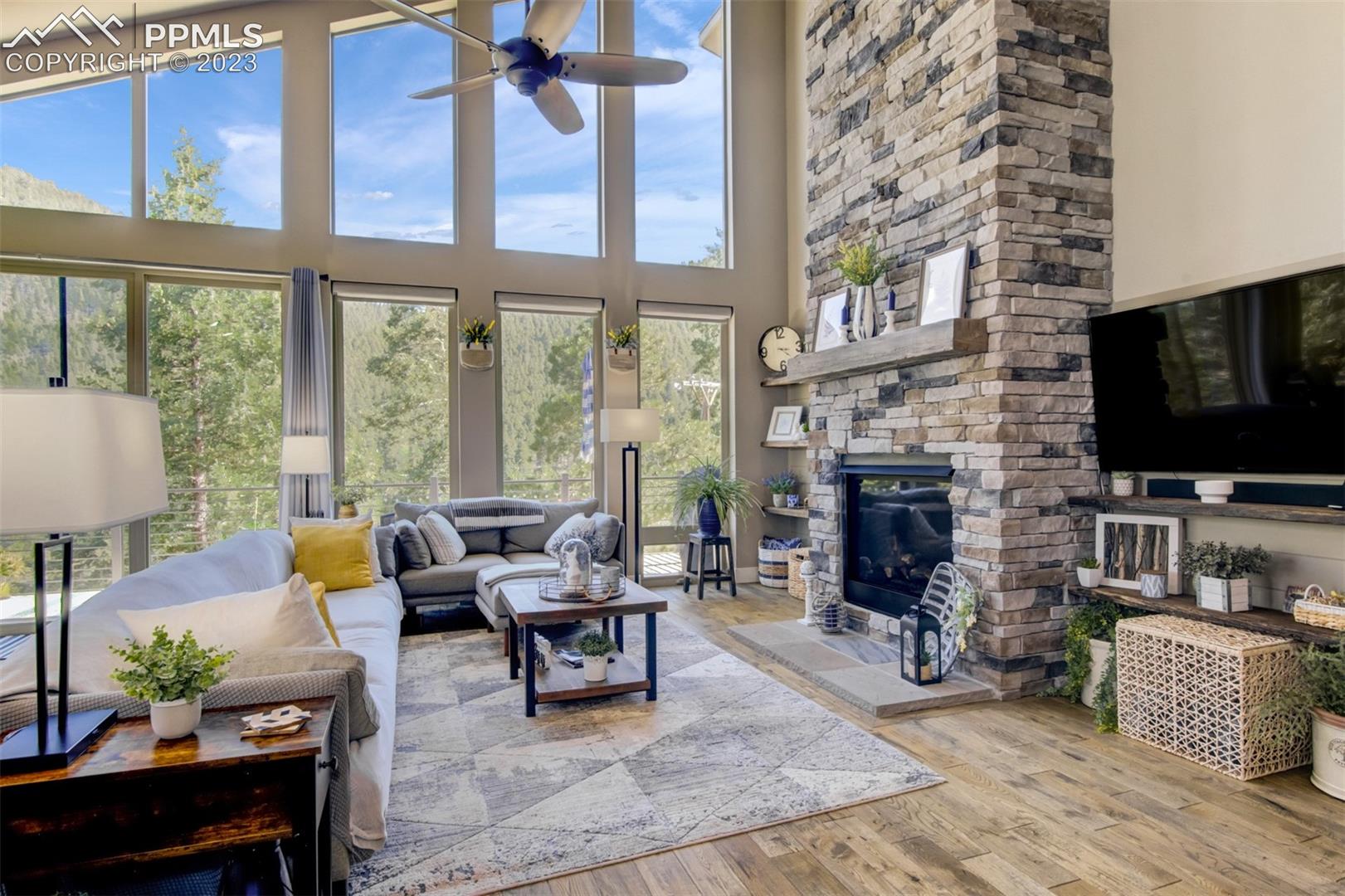 5020 South High Ridge View Manitou Springs, CO 80829 - Photo 14 of 46 Wonderful open concept living room with a propane burning fireplace, custom reclaimed barn wood mantle, large windows for natural lighting, solid white oak flooring and views that never grow old!!!