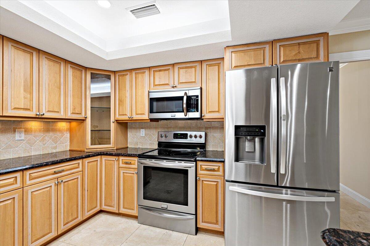 3261 Southeast Fairway West Stuart, FL 34997 - Photo 39 of 44 a kitchen with granite countertop stainless steel appliances a refrigerator stove and microwave