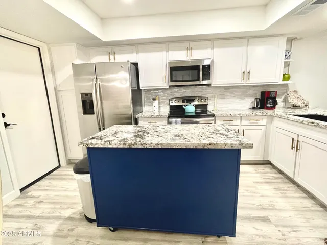 a kitchen with stainless steel appliances granite countertop a refrigerator a stove a sink a microwave a counter space and cabinets