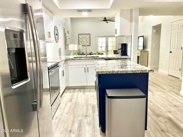 a kitchen with stainless steel appliances granite countertop a refrigerator a stove and white cabinets