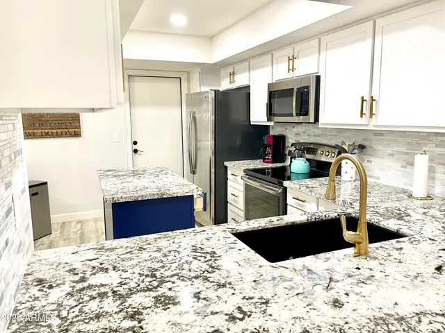 a kitchen with stainless steel appliances kitchen island granite countertop a sink stove and refrigerator