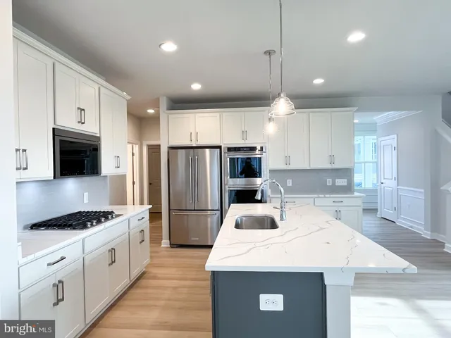 a kitchen with stainless steel appliances kitchen island granite countertop a sink a stove a refrigerator and cabinets