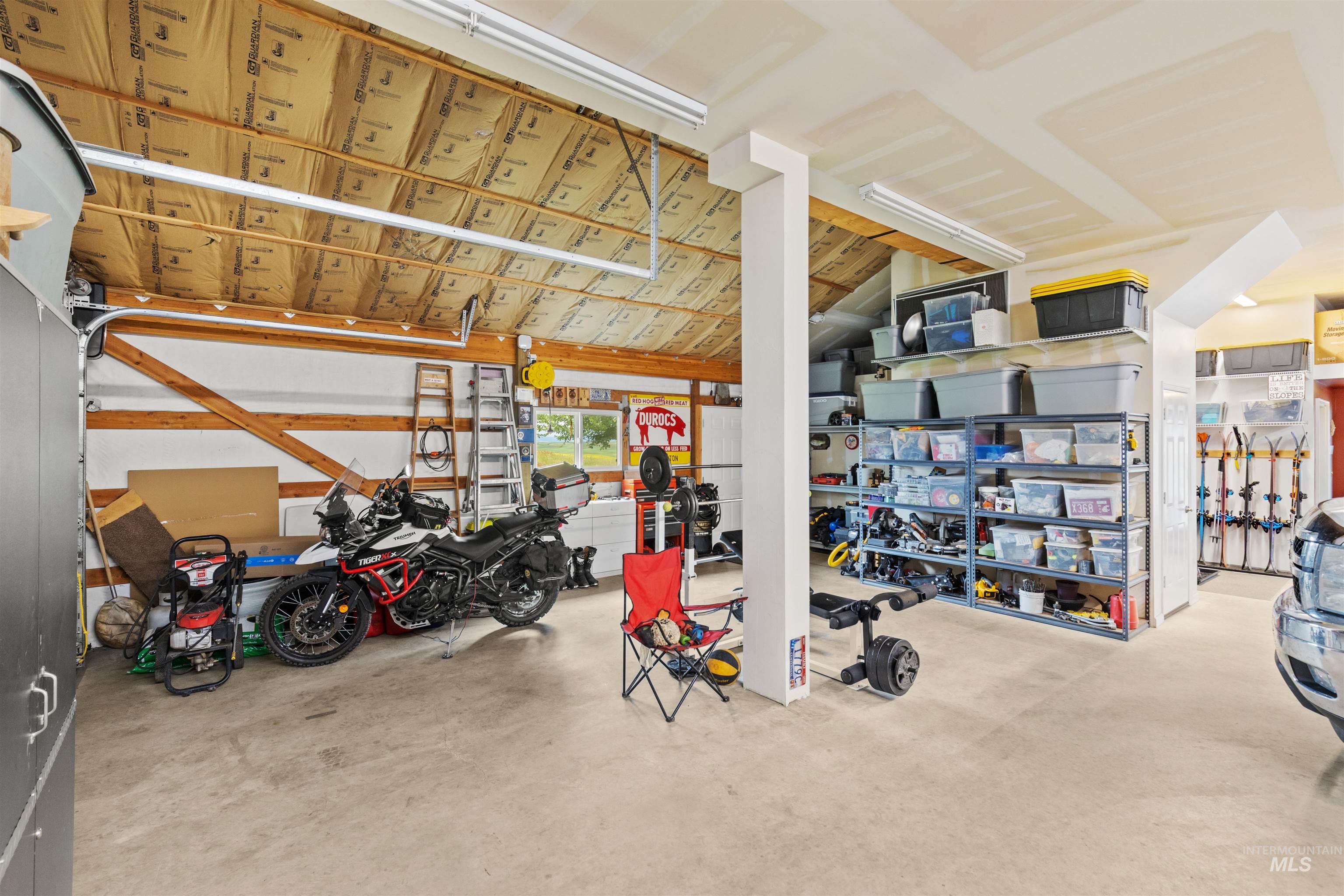 1513 Uniontown Road Genesee, ID 83832 - Photo 42 of 50 Spacious garage featuring a concrete floor, exposed wood beam ceiling, ample storage shelving, and multiple windows providing natural light