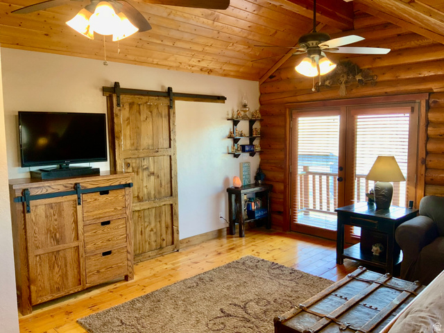 76 Highway 118 Monroe, UT 84754 - Photo 38 of 76 Living room featuring a ceiling fan, log walls, wood ceiling, a barn door, and light wood-style flooring