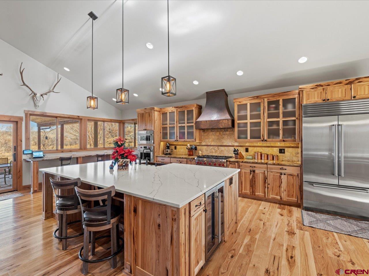 7528 South River Road Olathe, CO 81425 - Photo 12 of 44 a kitchen with stainless steel appliances granite countertop a kitchen island a stove a sink a dining table and chairs with wooden floor