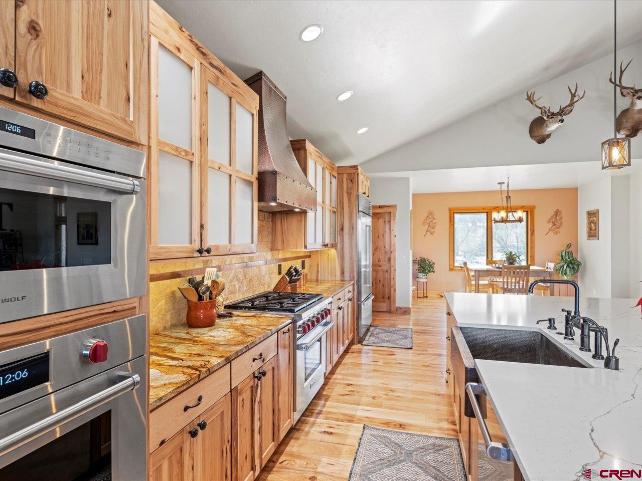 7528 South River Road Olathe, CO 81425 - Photo 14 of 44 a large kitchen with stainless steel appliances a stove a sink dishwasher and cabinets with wooden floor