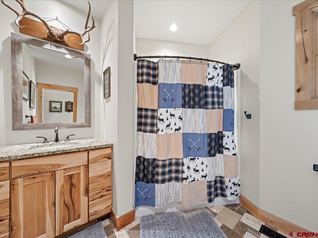 7528 South River Road Olathe, CO 81425 - Photo 23 of 44 a bathroom with a granite countertop sink a mirror a vanity and shower