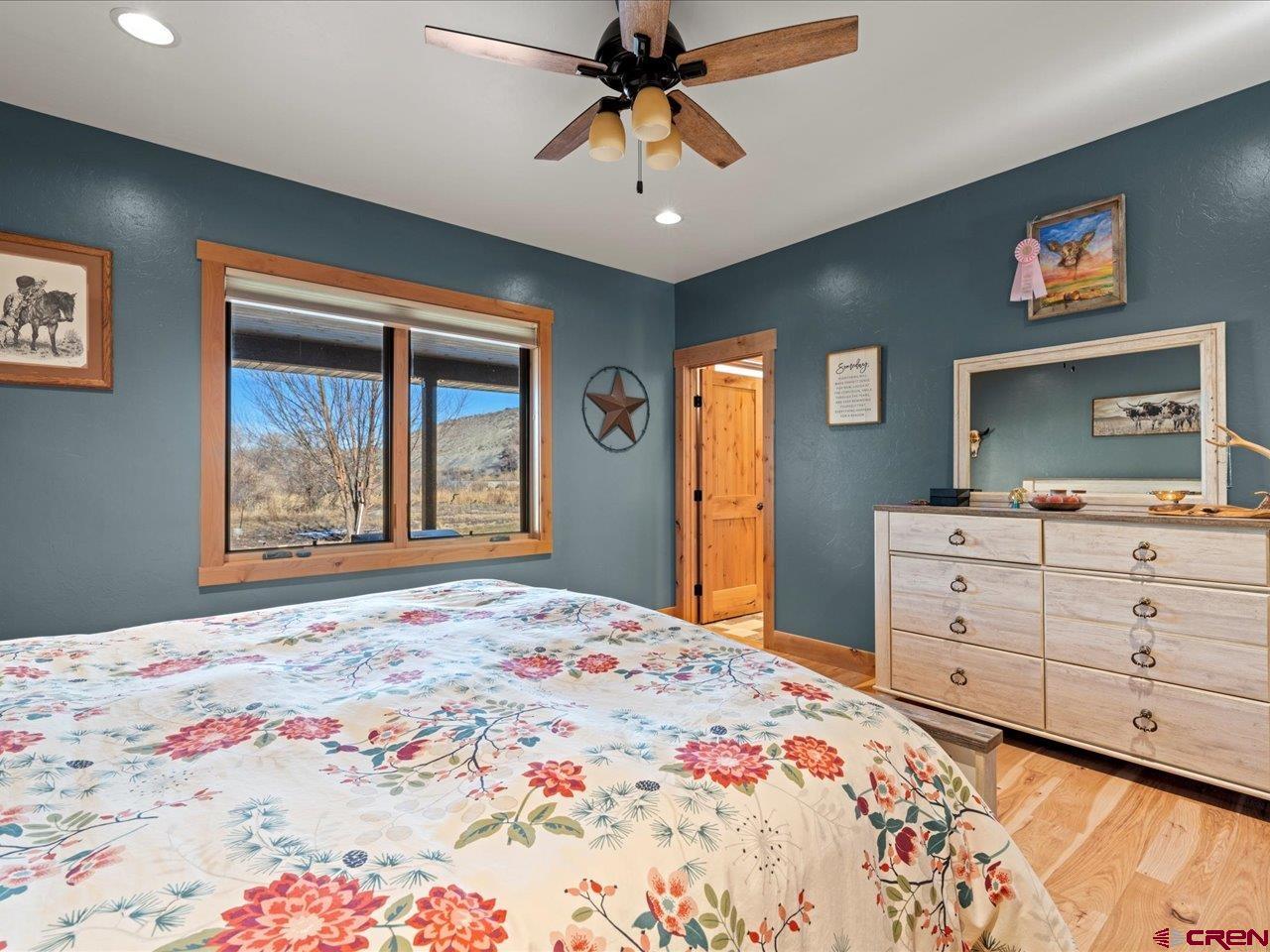 7528 South River Road Olathe, CO 81425 - Photo 27 of 44 a bedroom with a large bed and a chandelier