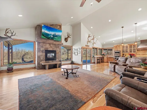 a kitchen with stainless steel appliances granite countertop a kitchen island a stove a sink a dining table and chairs with wooden floor