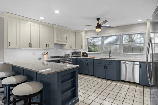 a kitchen with stainless steel appliances granite countertop a sink a stove a dining table and chairs