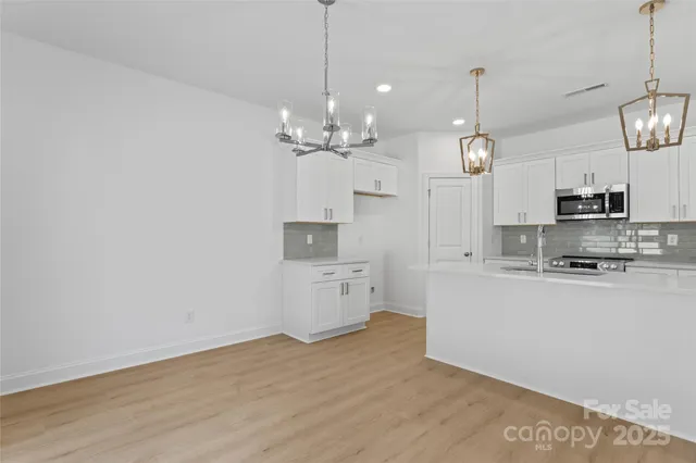 a large kitchen with cabinets wooden floor and stainless steel appliances