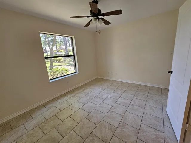 an empty room with windows and fan