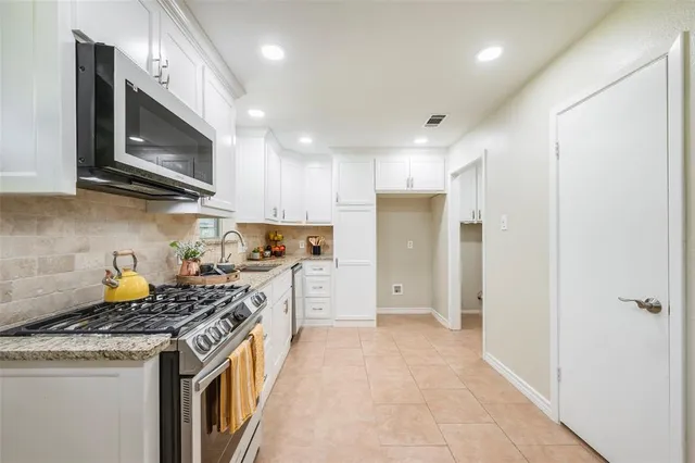 a kitchen with stainless steel appliances granite countertop a stove a sink and a refrigerator