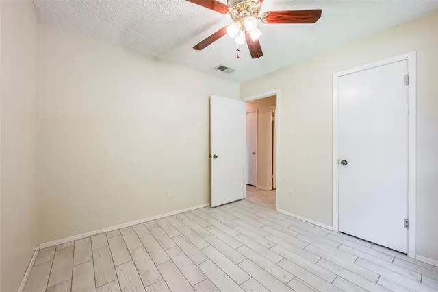 an empty room with closet and a chandelier fan