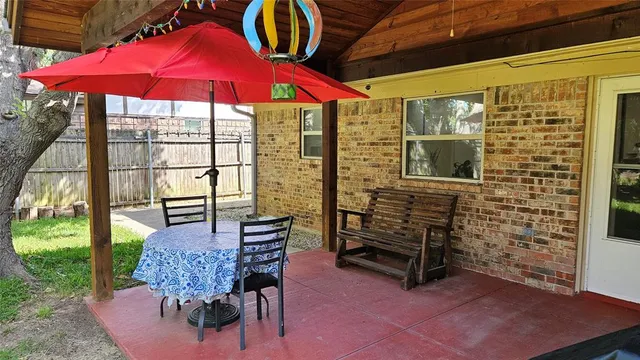a view of a balcony with chairs and red umbrella