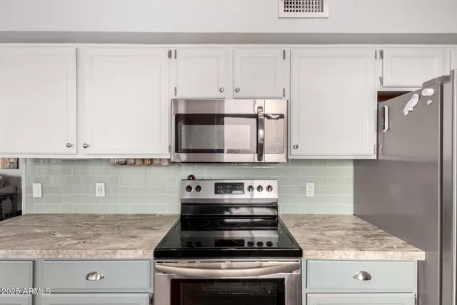 a kitchen with granite countertop white cabinets and stainless steel appliances