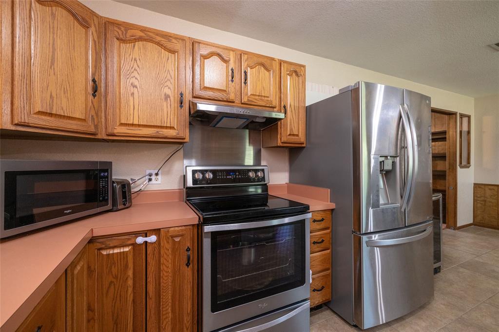151 County Road 3699 Springtown, TX 76082 - Photo 8 of 35 Kitchen featuring wood cabinetry, stainless steel appliances, and a terracotta-toned countertop
